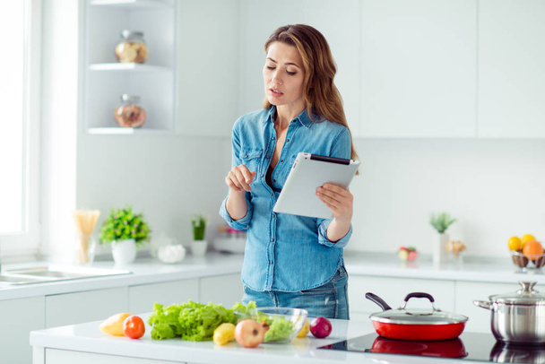 Portrait of her she nice lovely attractive focused concentrated brown-haired lady using new recipe fresh hot dish meal dinner lunch delicacy in light white interior style kitchen - Фото, зображення