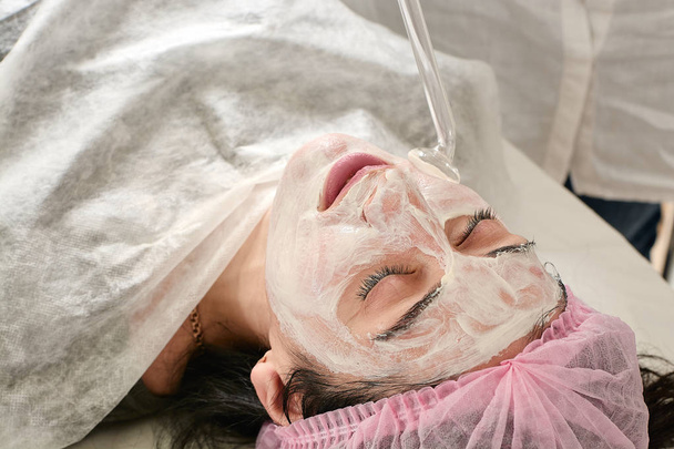 Jonge vrouw in schoonheidssalon doet verjongende, toning procedure darsonval op het gezicht. - Foto, afbeelding