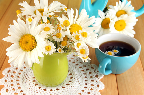Beautiful bouquet chamomiles in pitcher on wooden table close-up - 写真・画像