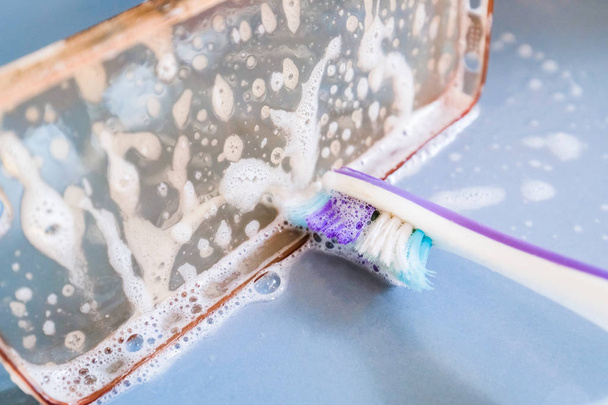 Limpieza de la funda del teléfono de silicona con cepillo de dientes, espuma y jabón
 - Foto, Imagen