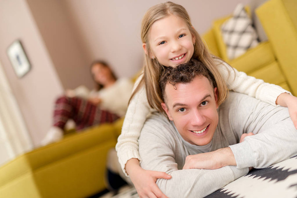 Beautiful smiling father and daughter having fun at living room and looking at camera. - Valokuva, kuva