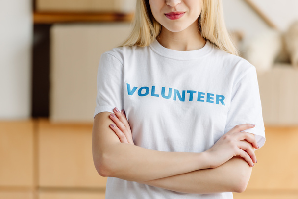 cropped view of girl in white t-shirt with volunteer inscription standing with crossed arms - Foto, immagini