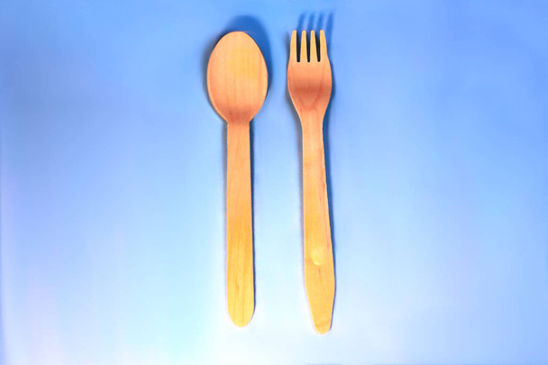 Disposable ecological wooden bamboo forks and spoons pattern on a blue background. Environment friendly flat lay with free copy space for text - Photo, Image