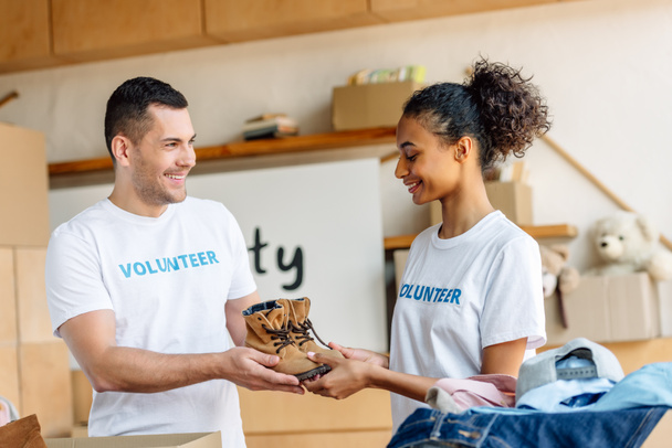 két fiatal, mosolygó multikulturális önkéntesek, akik gyerekcipőket a jótékonysági központban - Fotó, kép