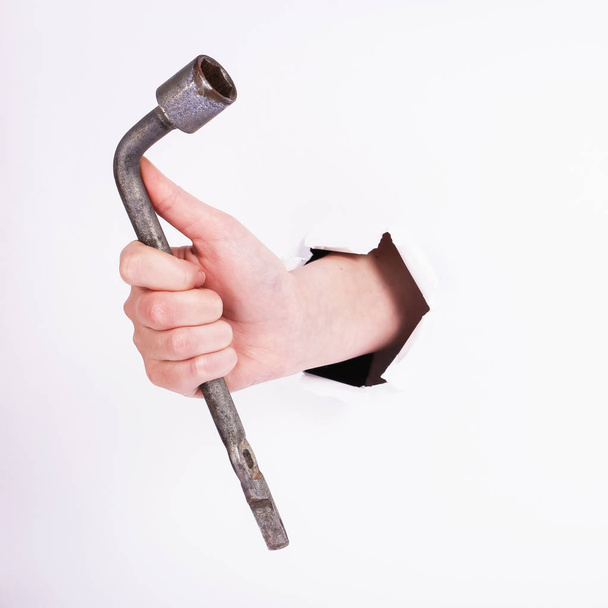 Wheel wrench in hand of the girl. Symbol of hard work, feminism and labor day. Isolate on white background. - Foto, Imagen