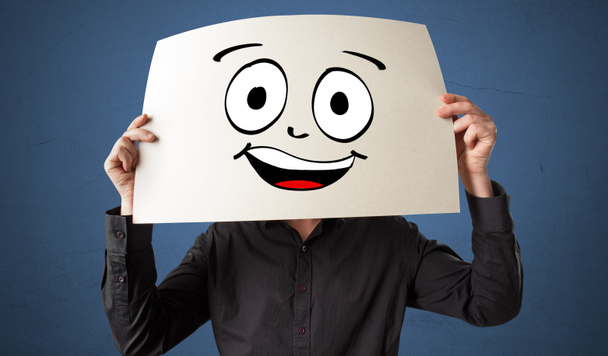 Student holding a paper with laughing emoticon in front of his face - Photo, Image