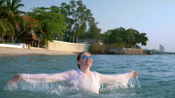 happy business woman in suit and dark glasses is splashing in the sea at luxury resorts. The concept of a long-awaited vacation, freelancing. - Фото, зображення