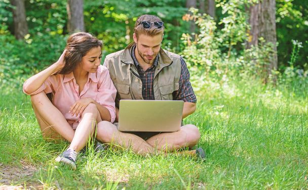 Couple youth spend leisure outdoors with laptop. Man and girl looking at laptop screen. Closer to nature. Modern technologies give opportunity to be online and work in any environment conditions - Photo, image