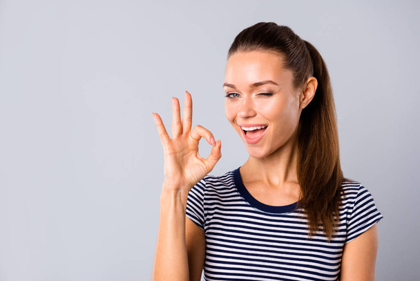 Close up photo beautiful amazing she her lady show ideal teeth self-confident okey symbol hand arm blink eye advising buy buyer new product wear blue white striped t-shirt isolated grey background - Foto, imagen