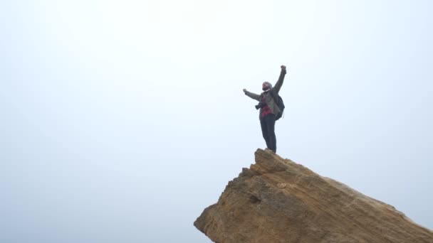 альпинист на вершине горы поднял руки в небо
 - Кадры, видео