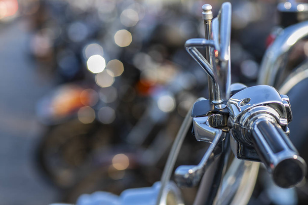 The chromed handlebar of a motorcycle.  View of motorcycle handlebar in the background many motorbikes blurred.  - Photo, Image