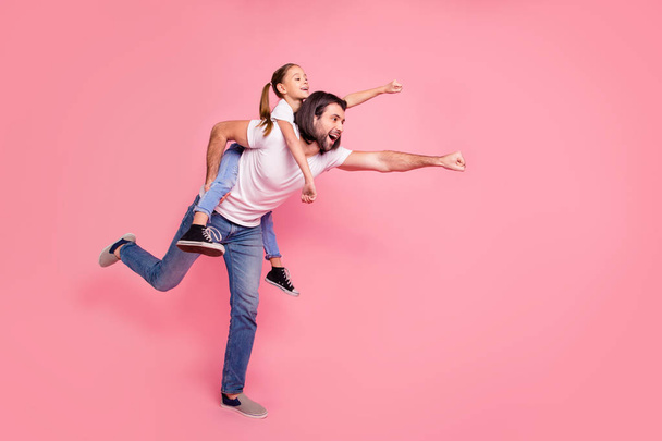Full length side profile body size photo she her little lady he him his daddy dad hold little princess piggyback hands arms ready fly wear casual white t-shirts denim jeans isolated pink background - Valokuva, kuva
