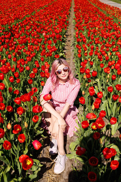 Усміхнена дівчина-підліток проходить через поле тюльпанів
 - Фото, зображення
