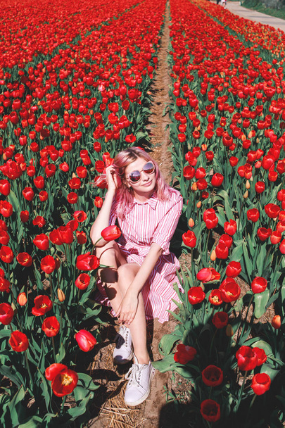 Smiling teenage girl walks through tulip field - Foto, immagini