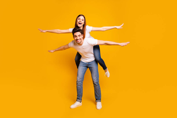 Full length body size view portrait of his he her she two nice attractive cheerful cheery optimistic people having fun trip fly isolated over vivid shine bright yellow background - 写真・画像