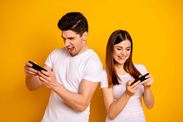 Portrait of his he her she two nice attractive lovely stylish trendy cheerful cheery positive people enjoying playing app contest isolated over vivid shine bright yellow background - Photo, image