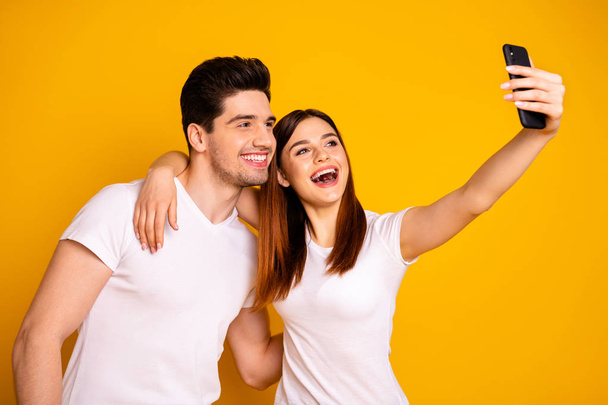 Portrait of his he her she two nice attractive stylish trendy cheerful cheery positive people making taking selfie isolated over vivid shine bright yellow background - Fotó, kép