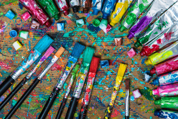 Vue de dessus. Vieille table d'artiste tachée avec tubes de peinture acrylique et pinceaux. Contexte artistique
 - Photo, image