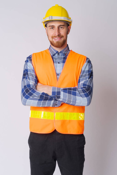Feliz joven barbudo trabajador de la construcción sonriendo con los brazos cruzados
 - Foto, Imagen