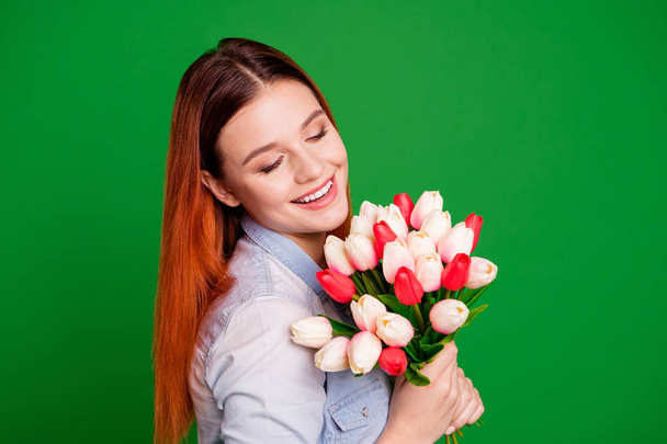 Close up side profile photo beautiful she her lady hands arms hold flowers morning 8 march overjoyed expression best surprise husband wear casual jeans denim shirt isolated green bright background - Zdjęcie, obraz