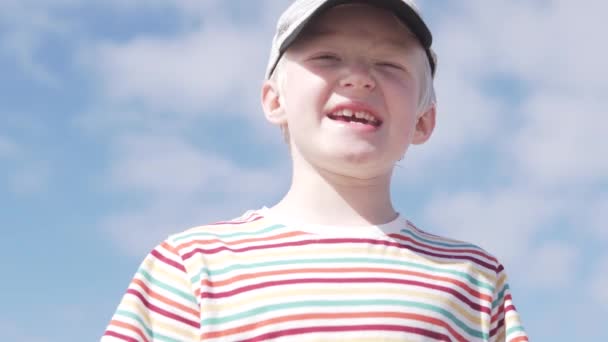 Knappe jongen Blond in een pet op zijn hoofd tegen de hemel - Video