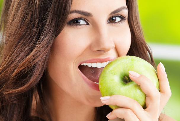 Young woman eating apple, outdoors - Fotografie, Obrázek