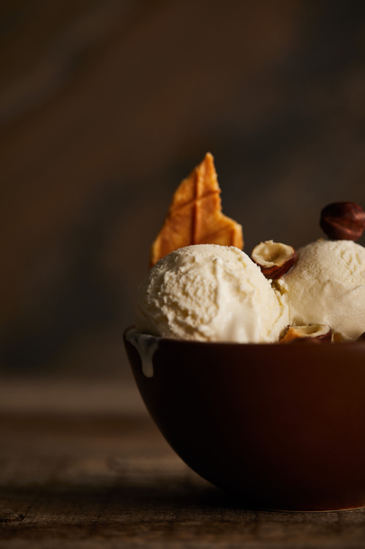 enfoque selectivo de deliciosas cucharadas de helado con trozo de waffle y avellanas en un tazón en la mesa
 - Foto, Imagen