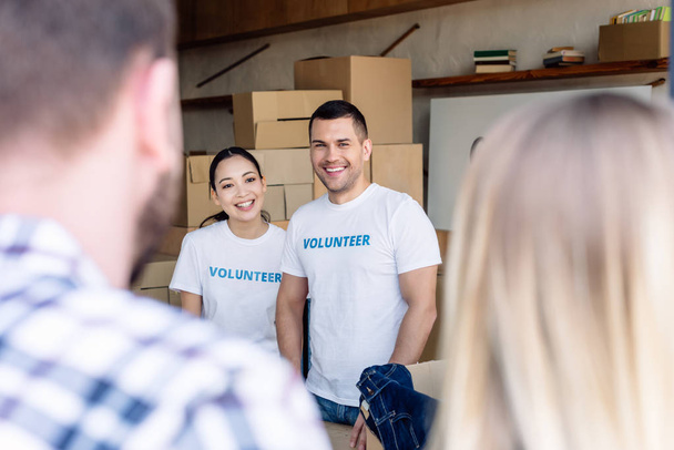 focus selettivo di volontari multiculturali sorridenti che incontrano persone nel centro di beneficenza
 - Foto, immagini
