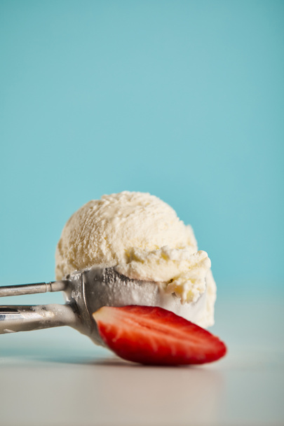scoop of ice cream in spoon and strawberry on blue with copy space - 写真・画像
