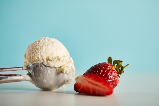 scoop of ice cream in spoon and strawberries on blue with copy space - Fotografie, Obrázek