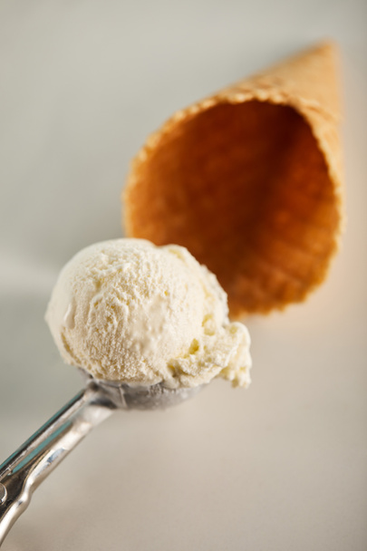 επιλεκτική εστίαση της σέσουλα παγωτού σε κουτάλι και βάφλα κώνος σε γκρι - Φωτογραφία, εικόνα