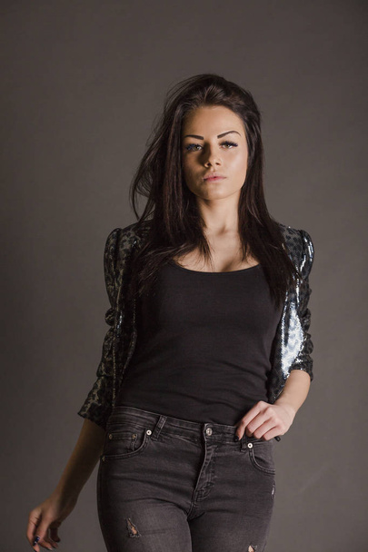 young brunette woman wearing shiny leopard jacket posing in studio - Fotografie, Obrázek