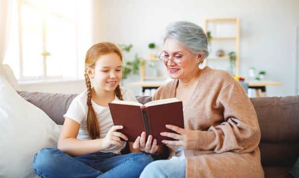 happy family grandmother reading to granddaughter book at home   - Photo, Image