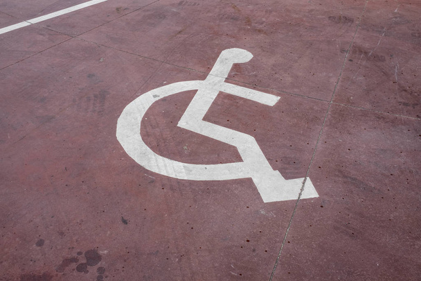 panneau de stationnement blanc handicapés peint sur un plancher rouge
 - Photo, image