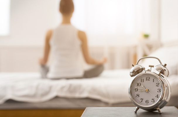 Yoga tijd. Vrouw mediterend op bed in lotushouding - Foto, afbeelding