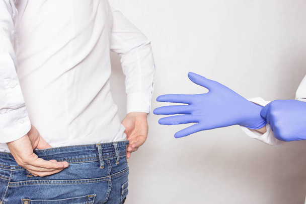 Doctor urologist puts a medical glove on the arm to examine the patient's prostate, prostate massage, lymphatic drainage - Foto, afbeelding
