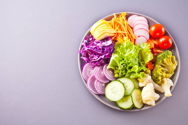 Healthy vegetable buddha bowl lunch with quinoa, red cabbage, tomatoes, onion, green salad, cucumber on gray background. Top view. Copy space. - Фото, зображення