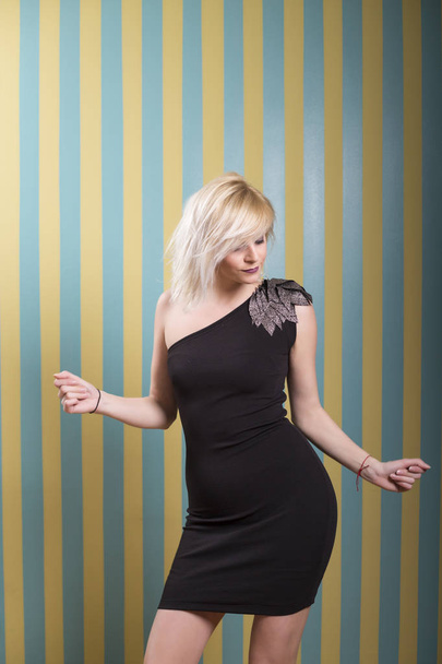 Attractive young blonde woman posing in front of striped yellow blue background - Fotografie, Obrázek