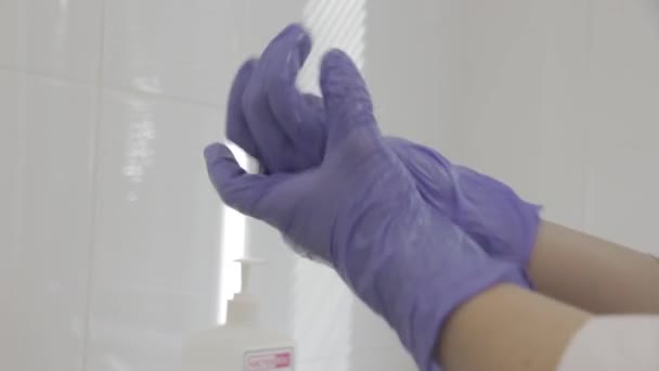 Ο γιατρός απολυμαίνει τα γάντια πριν από την εξέταση του ασθενούς - Πλάνα, βίντεο