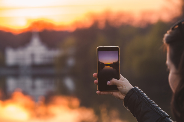 femme prenant une photo du coucher du soleil sur son téléphone
 - Photo, image