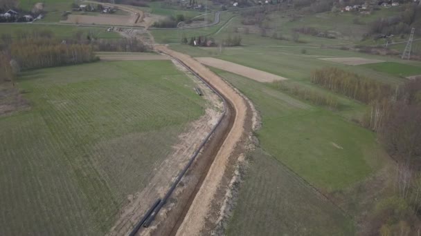 Laying gas pipeline among green hills. Large high-pressure steel pipes prepared for immersion in the excavated trench. Land works in the strategic industry. Energy and natural resources - Footage, Video