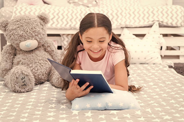 Story concept. Happy girl read interesting story. Little child ejoy bedtime story in bed. Good night story - Фото, изображение