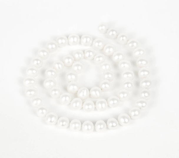 Pearl necklace laid out in spiral over white background - Foto, Bild