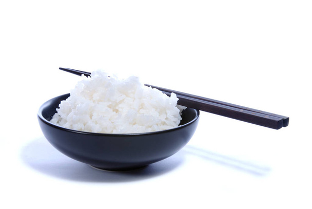 Black bowl with white rice and chop sticks isolated on white. - Foto, imagen