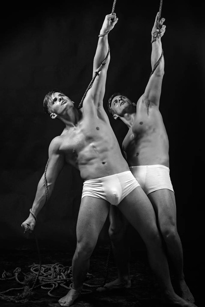 two gymnastic acrobatic caucasian men twins in same pose. - 写真・画像