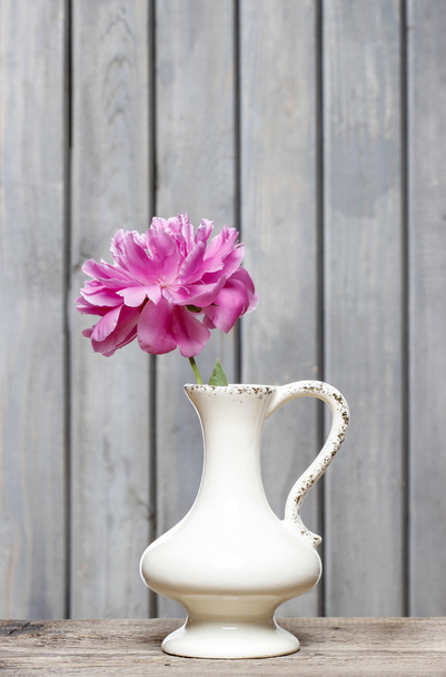 Single pink peony in white vase on wooden rustic background - Foto, Imagen