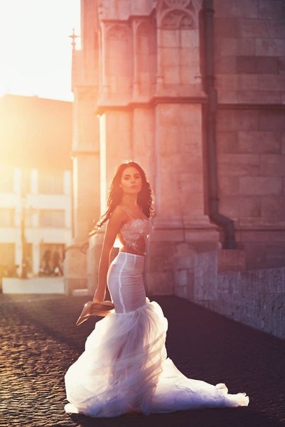 Bride girl at wedding ceremony in castle. Woman at stone ancient tower in summer. Sexy girl in white dress with stylish hair. Wedding fashion and beauty salon. Fashion model or princess in dress - Фото, зображення