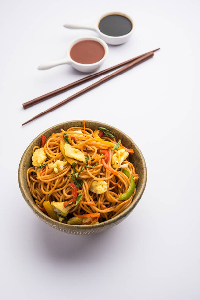 Egg Schezwan/hakka noodles, popular indochinese food served in a bowl with chopsticks. selective focus - Photo, image