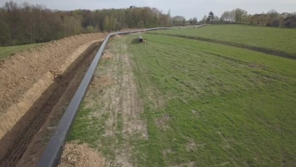 Laying gas pipeline among green hills. Large high-pressure steel pipes prepared for immersion in the excavated trench. Land works in the strategic industry. Energy and natural resources - Footage, Video