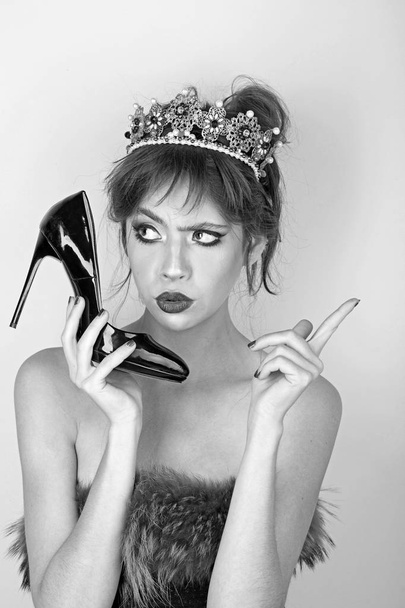 Fashion girl with elegant look and makeup. Beauty queen and fashion. Luxury of woman in crown jewelry and shoe as phone. Communication and fetish, hairdresser. Makeup for woman with soft skin. - 写真・画像